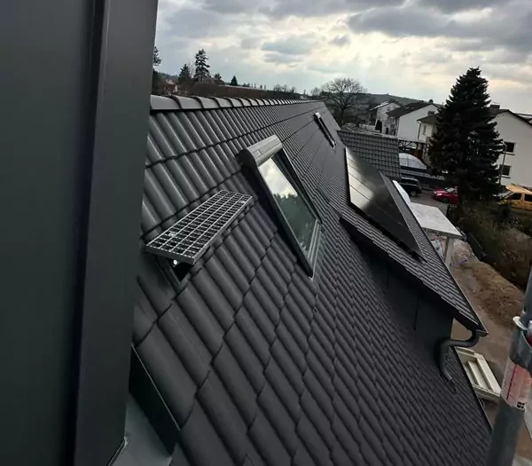 Blick auf ein Steildach mit Dachfenstern und Solarpanelen