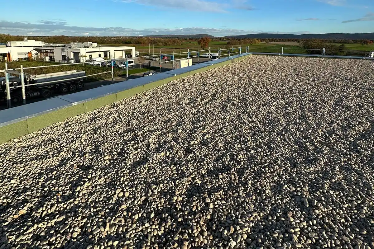 Flachdach mit Sand/Steinen mit Blick auf eine hügelige Landschaft